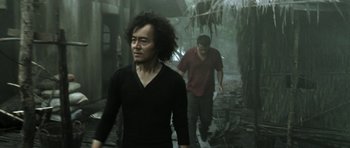 Movie still from “Vinyan” (2008), directed by Fabrice du Welz – A man and a woman walking through a forest; Medium shot, Low angle