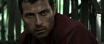 Movie still from “Vinyan” (2008), directed by Fabrice du Welz – A person wearing a red shirt; Close Up shot, Over the shoulder angle