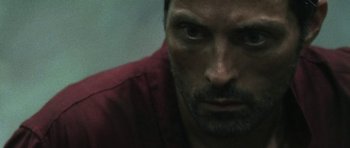 Movie still from “Vinyan” (2008), directed by Fabrice du Welz – A person with a red shirt on; Close Up shot, Over the shoulder angle