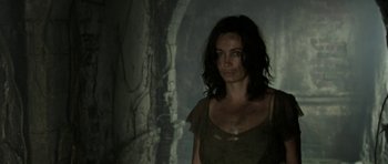 Movie still from “Vinyan” (2008), directed by Fabrice du Welz – A woman standing in front of a tree in the dark; Medium shot, Low angle