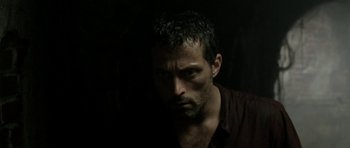Movie still from “Vinyan” (2008), directed by Fabrice du Welz – A person wearing a brown shirt; Close Up shot, High angle