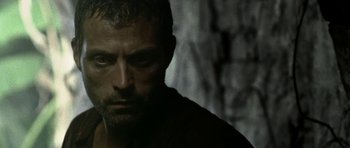 Movie still from “Vinyan” (2008), directed by Fabrice du Welz – A man's face in a dark room; Close Up shot, Low angle