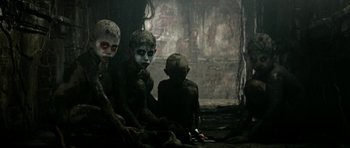 Movie still from “Vinyan” (2008), directed by Fabrice du Welz – A group of young boys sitting next to each other in a dark room; Wide shot, High angle