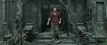 Movie still from “Vinyan” (2008), directed by Fabrice du Welz – A man walking down the steps of a building; Wide shot, Low angle