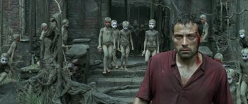 Movie still from “Vinyan” (2008), directed by Fabrice du Welz – A group of people with painted faces walking down a set of stairs; Medium shot, High angle