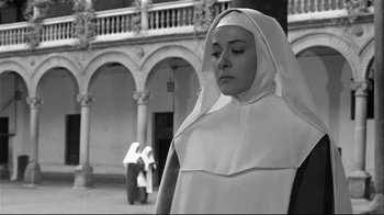 Movie still from “Viridiana” (1961), directed by Luis Buñuel – A woman in a nun's outfit standing in front of a building; Medium shot, Low angle