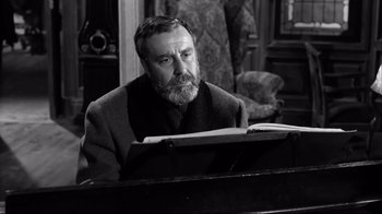 Movie still from “Viridiana” (1961), directed by Luis Buñuel – An older man sitting in front of an open book; Close Up shot, Low angle