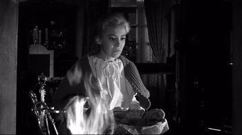Movie still from “Viridiana” (1961), directed by Luis Buñuel – A woman sitting at a table with a basket of food; Medium shot, Low angle