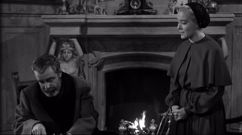 Movie still from “Viridiana” (1961), directed by Luis Buñuel – A man and a woman standing in front of a fireplace; Medium shot, Over the shoulder angle