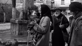 Movie still from “Viridiana” (1961), directed by Luis Buñuel – A woman holding a baby in her arms while standing next to an older man; Medium shot, Low angle