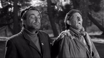 Movie still from “Viridiana” (1961), directed by Luis Buñuel – Two older men standing next to each other in a wooded area; Medium shot, Low angle