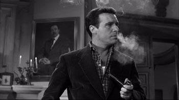 Movie still from “Viridiana” (1961), directed by Luis Buñuel – A black and white photo of a man smoking a pipe; Medium shot, Low angle