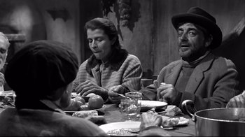 Movie still from “Viridiana” (1961), directed by Luis Buñuel – A group of people sitting at a table eating food; Medium shot, High angle