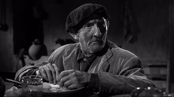 Movie still from “Viridiana” (1961), directed by Luis Buñuel – An old man sitting at a table with a plate in front of him; Close Up shot, Low angle