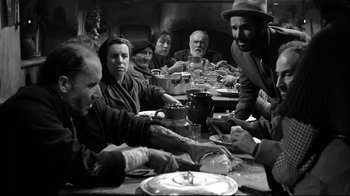 Movie still from “Viridiana” (1961), directed by Luis Buñuel – A group of people sitting at a table with food; Medium shot, Low angle
