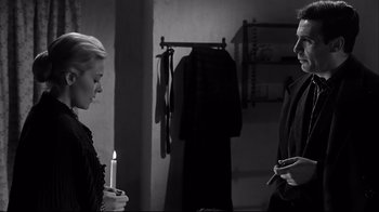 Movie still from “Viridiana” (1961), directed by Luis Buñuel – Two people standing next to each other holding candles; Medium shot, Over the shoulder angle