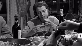 Movie still from “Viridiana” (1961), directed by Luis Buñuel – A woman sitting at a table with a glass of wine; Close Up shot, High angle