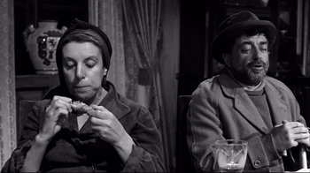 Movie still from “Viridiana” (1961), directed by Luis Buñuel – A man and a woman sitting at a dinner table; Medium shot, High angle