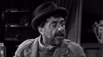 Movie still from “Viridiana” (1961), directed by Luis Buñuel – A man with a beard wearing a hat and a jacket; Close Up shot, Over the shoulder angle