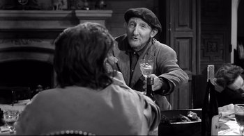 Movie still from “Viridiana” (1961), directed by Luis Buñuel – An older man holding a wine glass talking to a woman; Medium shot, Over the shoulder angle