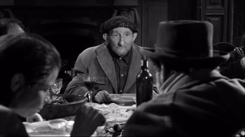 Movie still from “Viridiana” (1961), directed by Luis Buñuel – An old man sitting at a dinner table with a glass of wine; Medium shot, High angle
