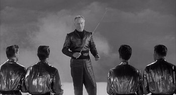 Movie still from “Visit to a Small Planet” (1960), directed by Norman Taurog – A man holding a sword in front of two other men; Medium shot, Low angle