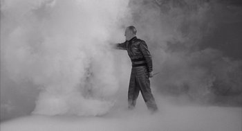 Movie still from “Visit to a Small Planet” (1960), directed by Norman Taurog – A man in a black suit is standing in the fog; Medium shot, Low angle