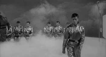 Movie still from “Visit to a Small Planet” (1960), directed by Norman Taurog – A group of men in silver suits standing in a cloud of smoke; Wide shot, Low angle