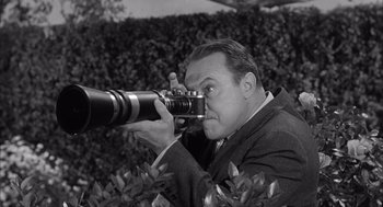 Movie still from “Visit to a Small Planet” (1960), directed by Norman Taurog – A black and white photo of a man taking a picture with a camera; Close Up shot, Low angle