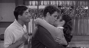 Movie still from “Visit to a Small Planet” (1960), directed by Norman Taurog – A man and a woman kissing in front of two other men; Medium shot, Over the shoulder angle