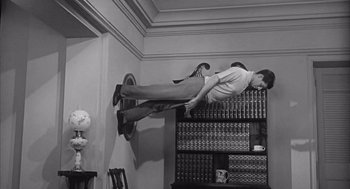 Movie still from “Visit to a Small Planet” (1960), directed by Norman Taurog – A man flying through the air on top of a bookshelf; Wide shot, Low angle