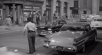 Movie still from “Visit to a Small Planet” (1960), directed by Norman Taurog – A black and white photo of a man and cars on a street; Wide shot, Over the shoulder angle