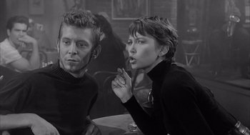 Movie still from “Visit to a Small Planet” (1960), directed by Norman Taurog – A man and a woman sitting at a table smoking a cigarette; Medium shot, Over the shoulder angle