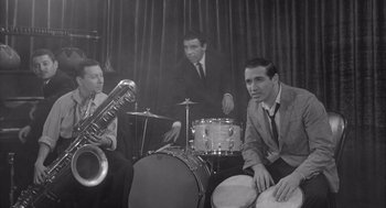 Movie still from “Visit to a Small Planet” (1960), directed by Norman Taurog – A group of men sitting around a drum set; Medium shot, High angle