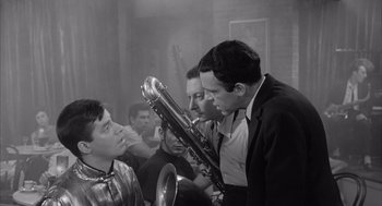Movie still from “Visit to a Small Planet” (1960), directed by Norman Taurog – A group of men standing next to each other holding instruments; Medium shot, Over the shoulder angle