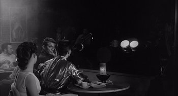 Movie still from “Visit to a Small Planet” (1960), directed by Norman Taurog – A black and white photo of a man sitting at a table; Medium shot, Over the shoulder angle