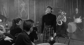 Movie still from “Visit to a Small Planet” (1960), directed by Norman Taurog – A woman standing in front of a group of people; Medium shot, Over the shoulder angle