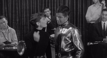 Movie still from “Visit to a Small Planet” (1960), directed by Norman Taurog – A man and a woman are standing next to each other in front of another man; Medium shot, Over the shoulder angle