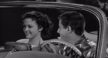 Movie still from “Visit to a Small Planet” (1960), directed by Norman Taurog – A man and a woman sitting in the driver's seat of a car; Close Up shot, Over the shoulder angle