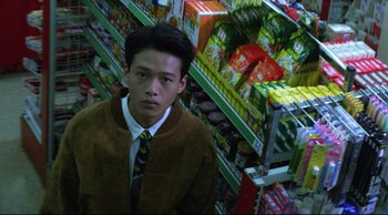 Movie still from “Vive L'Amour” (1994), directed by Tsai Ming-liang – A man in a brown jacket standing in a store; Medium shot, Overhead angle