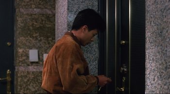 Movie still from “Vive L'Amour” (1994), directed by Tsai Ming-liang – A man in a brown jacket is looking at his cell phone; Medium shot, Over the shoulder angle