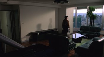 Movie still from “Vive L'Amour” (1994), directed by Tsai Ming-liang – A man standing in front of a window in a living room; Wide shot, High angle
