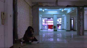 Movie still from “Vive L'Amour” (1994), directed by Tsai Ming-liang – A woman sitting on the ground in a room; Extreme Wide shot, High angle