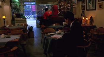 Movie still from “Vive L'Amour” (1994), directed by Tsai Ming-liang – A man sitting at a table in front of a woman; Wide shot, High angle