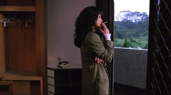 Movie still from “Vive L'Amour” (1994), directed by Tsai Ming-liang – A woman standing in front of a window smoking a cigarette; Medium shot, Over the shoulder angle