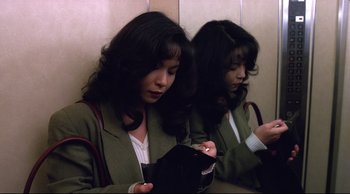 Movie still from “Vive L'Amour” (1994), directed by Tsai Ming-liang – A woman is looking at her purse in a mirror; Medium shot, High angle