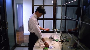 Movie still from “Vive L'Amour” (1994), directed by Tsai Ming-liang – A man in a white shirt and black tie is in a bathroom; Medium shot, Low angle