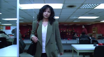 Movie still from “Vive L'Amour” (1994), directed by Tsai Ming-liang – A woman in a green jacket holding a black purse; Medium shot, Low angle