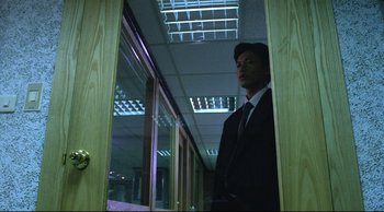 Movie still from “Vive L'Amour” (1994), directed by Tsai Ming-liang – A man in a suit standing in front of a window; Medium shot, Low angle