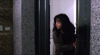 Movie still from “Vive L'Amour” (1994), directed by Tsai Ming-liang – A woman leaning against a door looking sad; Medium shot, High angle